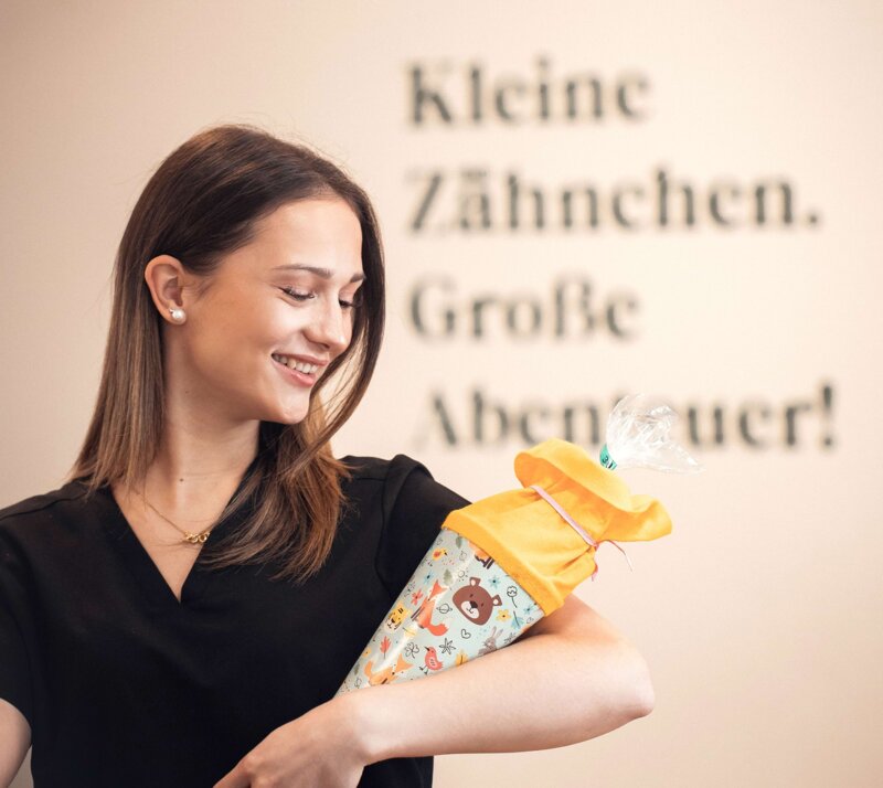 Mitarbeiterin hält lachend eine Schultüte.
